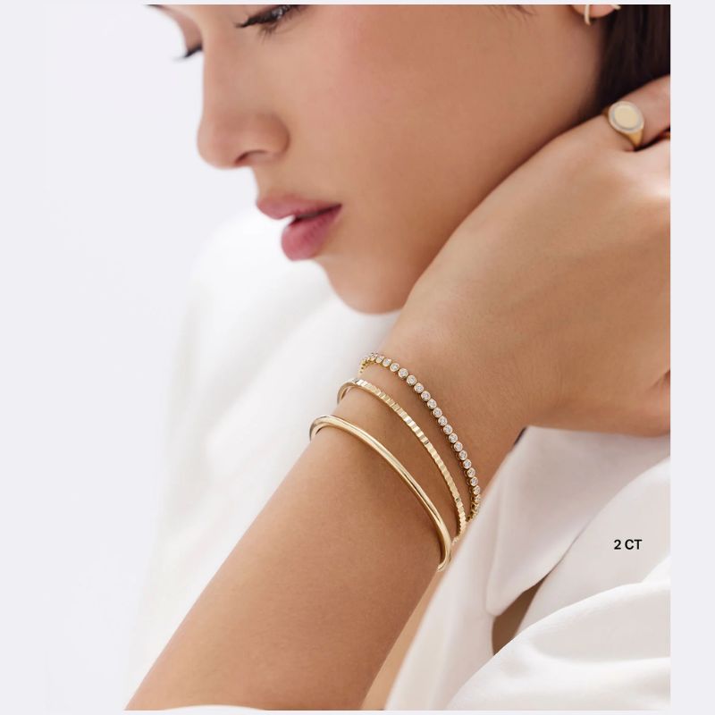 Model wearing an arm of gold and diamond tennis bracelets  