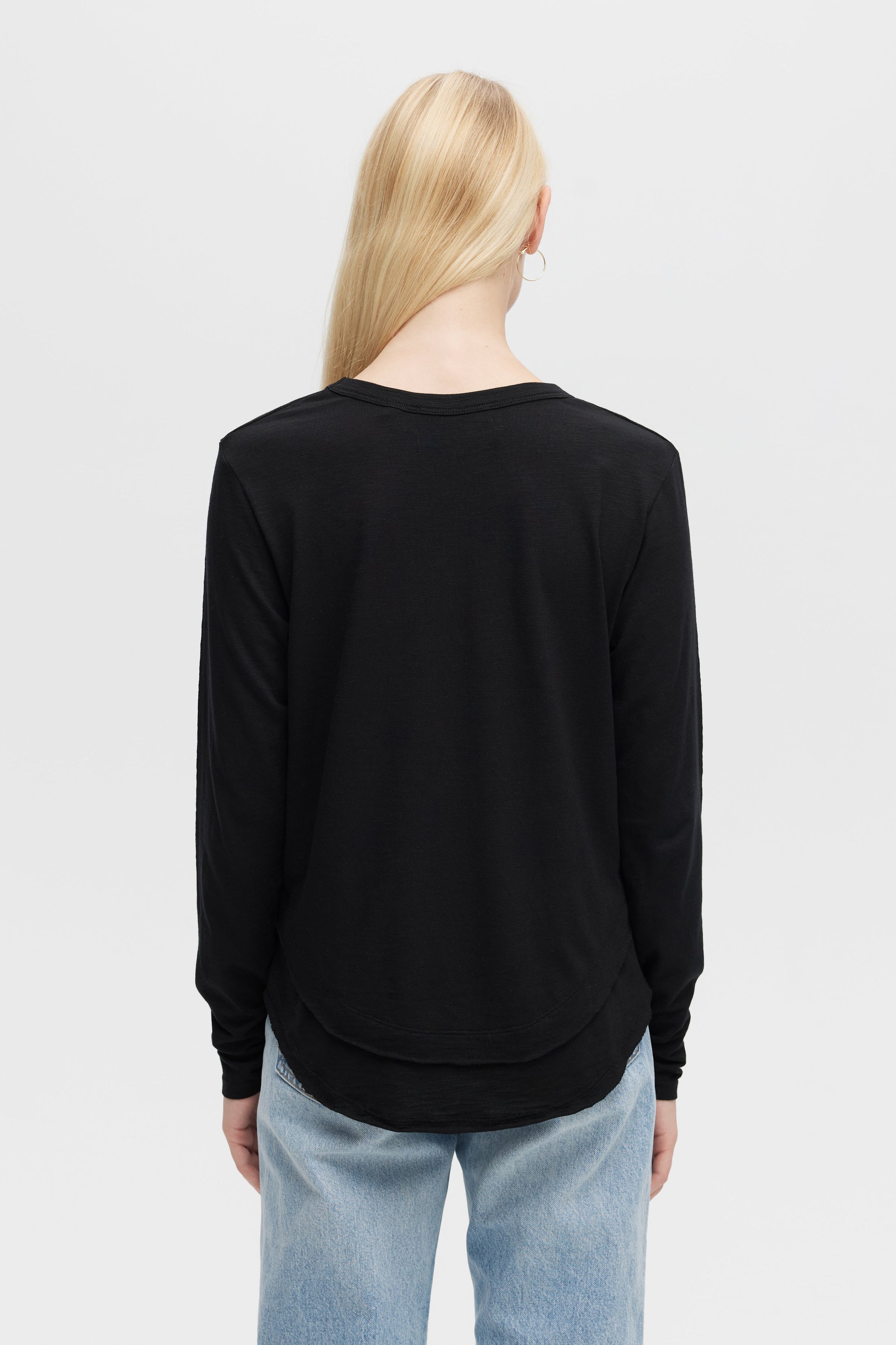 Model wearing Ava long sleeve top in black with hemline detail- Vack view 