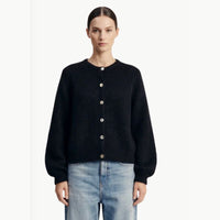 A black soft Alpaca wool cardigan has a crewneck and long sleeves and is paired with jeans on the model. 