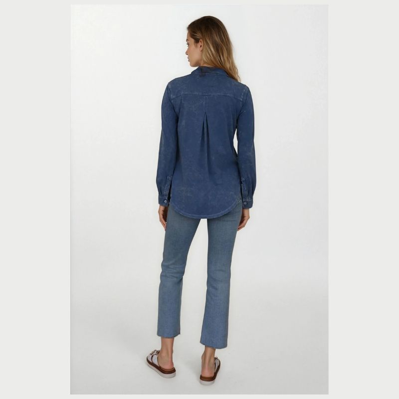 Woman wearingthe AMRAT long sleeve denim blue  collared button down shirt with jeans on a white background