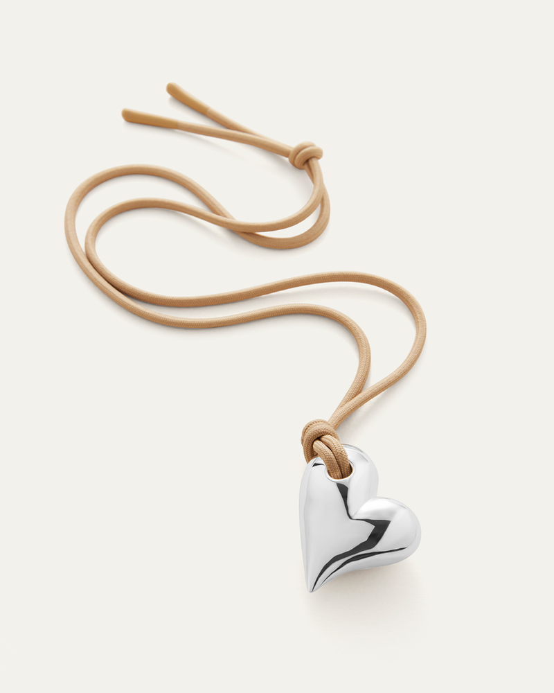 A  voluminous silver heart pendant on an adjustable beige cord - full view 