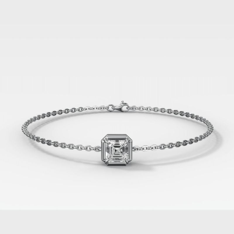 A white gold -toned chain bracelet featuring a central square emerald-cut diamond, displayed on a clean light gray background.