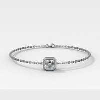 A white gold -toned chain bracelet featuring a central square emerald-cut diamond, displayed on a clean light gray background.
