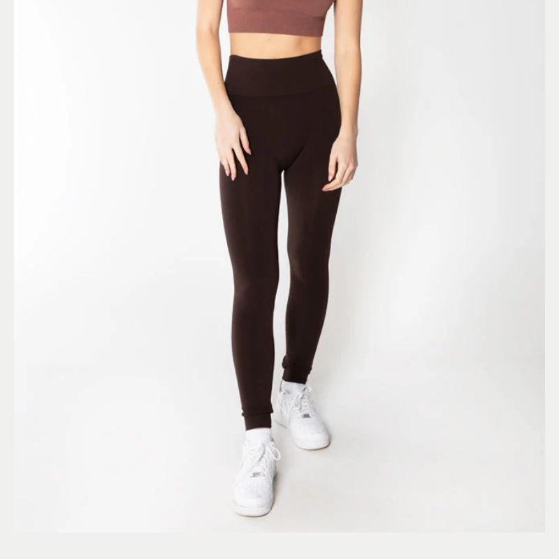 Person wearing black light-waisted leggings and white sneakers on a white background