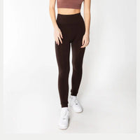 Person wearing black light-waisted leggings and white sneakers on a white background