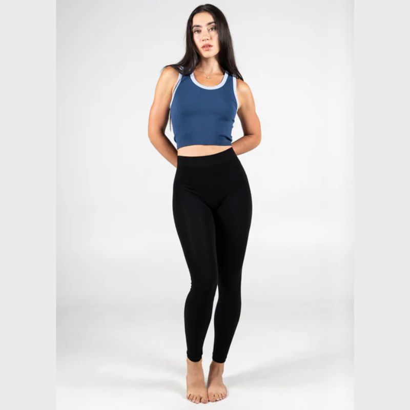 Woman wearing a blue tank top and black leggings on a white background