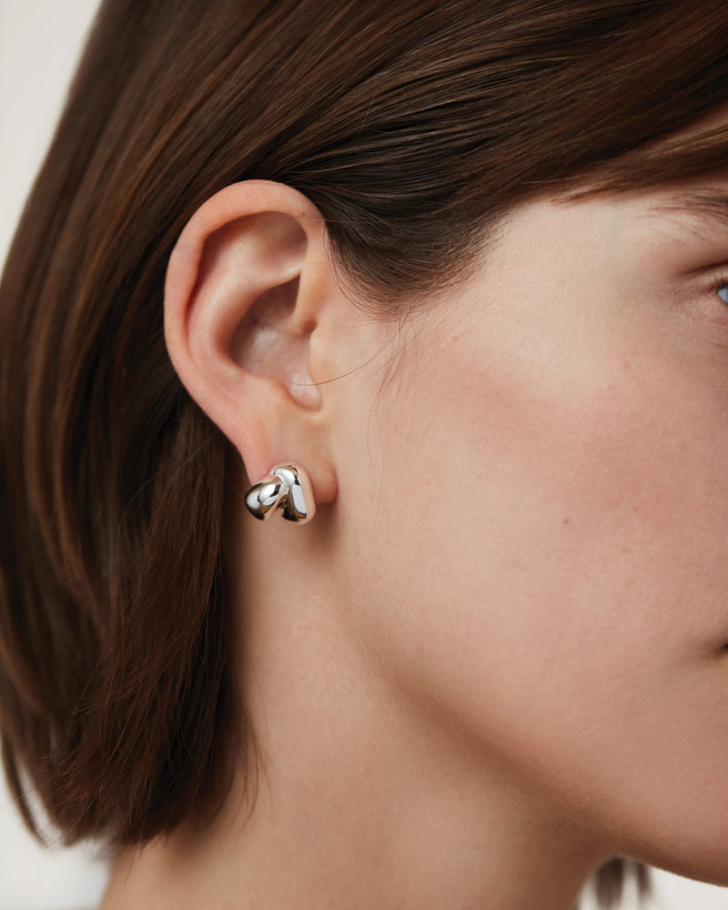 Close-up of a person wearing a silver hoop earring with a blurred background
