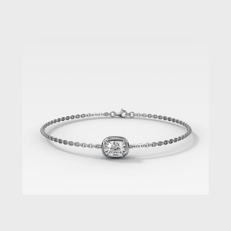A delicate white gold chain bracelet featuring a central cushion-cut diamond bezel-set in a polished silver frame, displayed on a clean light gray background.
