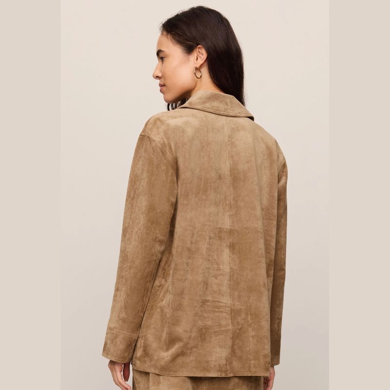 A woman shown from the back wearing a light brown suede or faux-suede blazer against a plain light beige studio background.