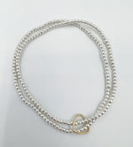 Two stretch bracelets made with 2mm silver beads. Uniquely connected with a 14k gold fil heart charm.   