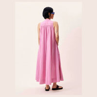 Back view of pink sleeveless maxi dress - model gas her hands in the pockets. 