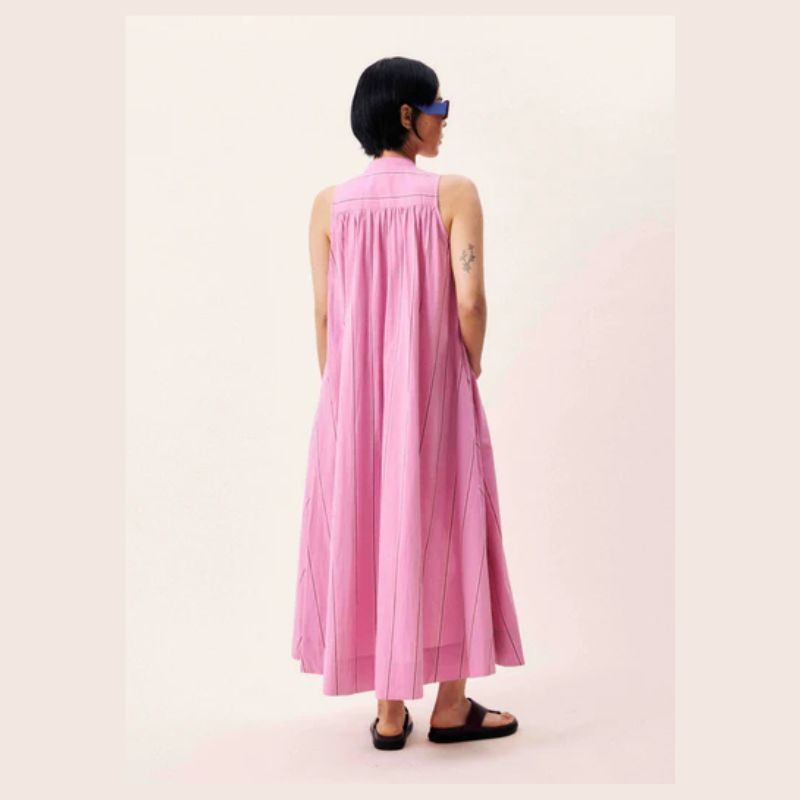 Back view of pink sleeveless maxi dress - model gas her hands in the pockets. 