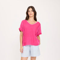 Woman wearing a bright pink top and light blue shorts on a white background