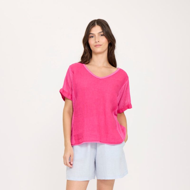 Woman wearing a bright pink top and light blue shorts on a white background