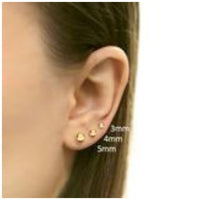 Gold earrings on an ear with size measurements indicated.
