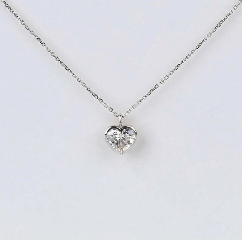 A delicate silver chain necklace with a small, clear heart-shaped crystal pendant, displayed against a clean white background.