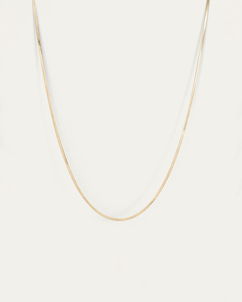 Gold chain necklace on a light beige background