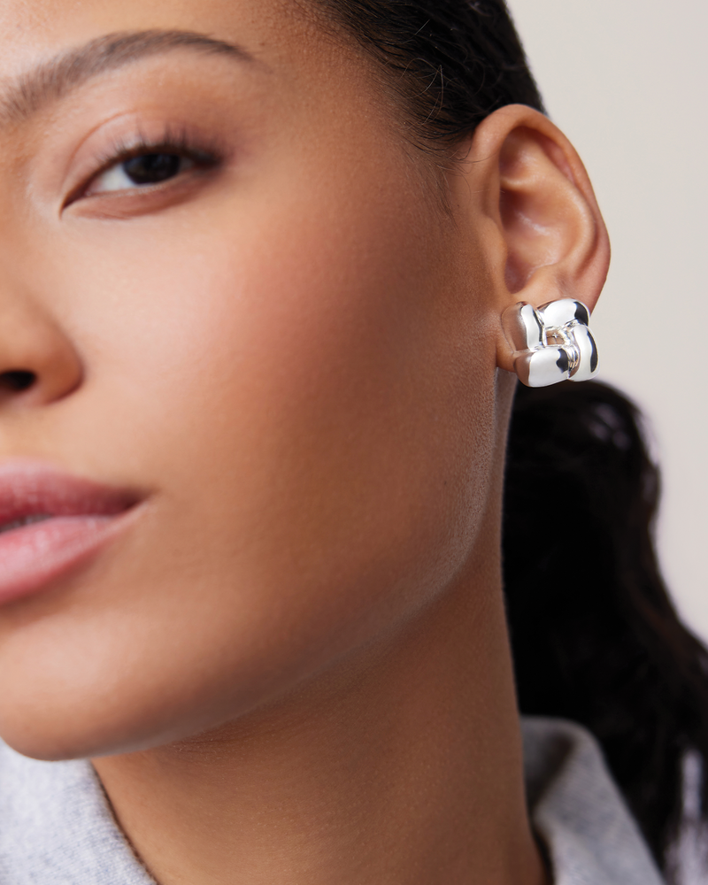 Close-up of a woman wearing silver earrings with a neutral background