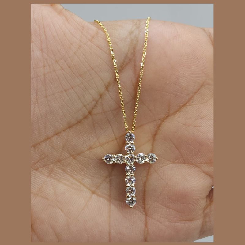 A white  gold cross pendant with lab diamond , displayed on a person's palm to show scale.