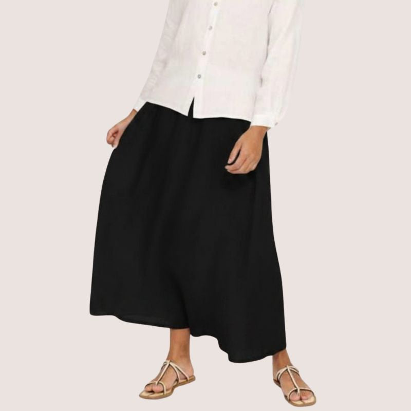Person wearing a long loose black  linen skirt with a white shirt. 
