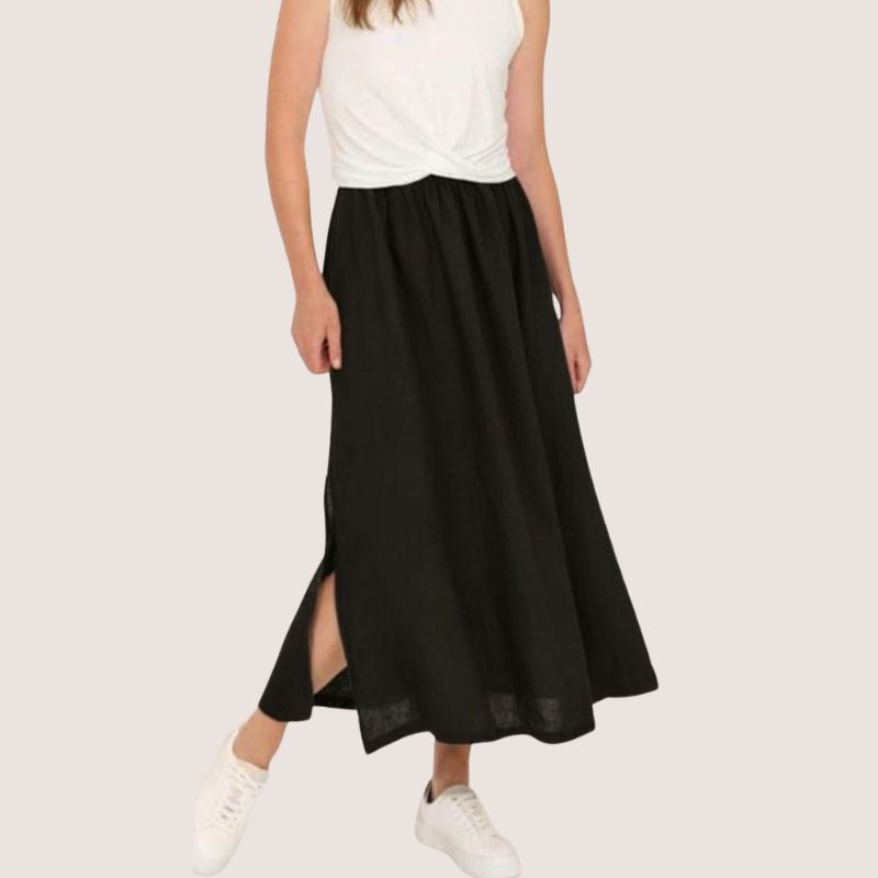 Person wearing The Pistache loose long linen skirt with a side split in Black and a white t- shirt.  