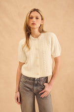 This cardigan is made of a beautiful, soft crème knit. It has short sleeves and a pearl-encrusted collar.