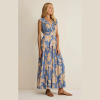 Woman wearing a V- neck blue and beige floral maxi dress against a plain background