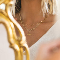 Close-up of a person wearing a gold necklace with a white background