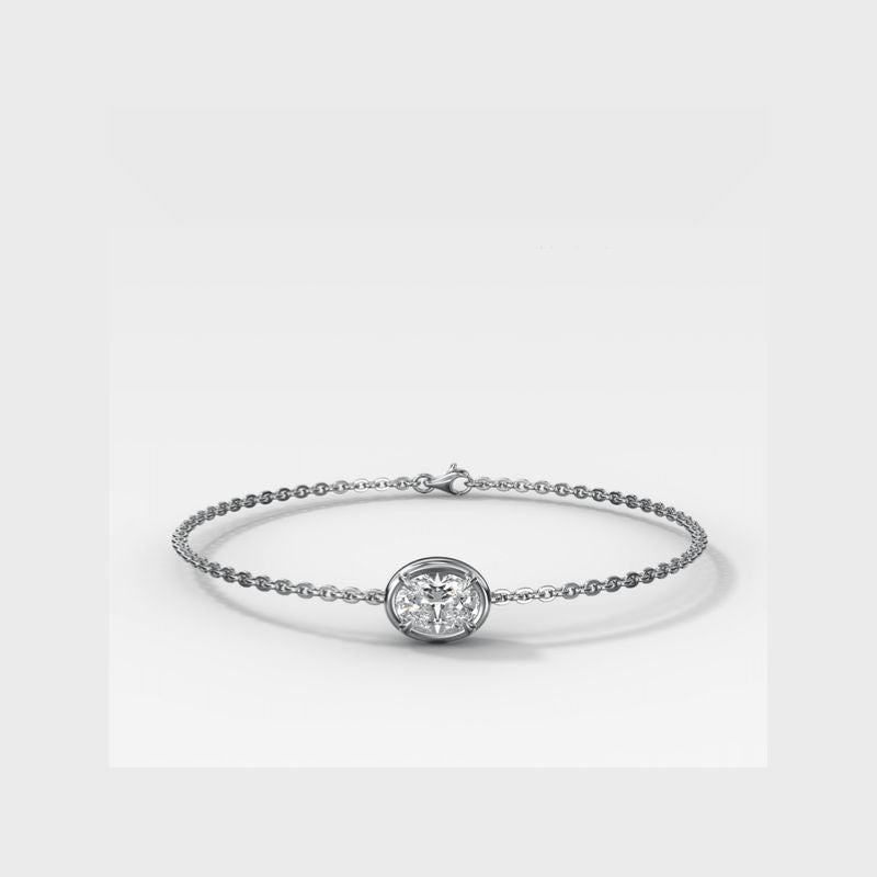 A delicate white gold chain bracelet featuring a central round bezel-set diamond, displayed on a clean light gray background.