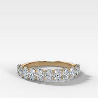 A yellow gold eternity ring featuring a row of oval-cut clear diamonds, set against a clean white background with a soft shadow.