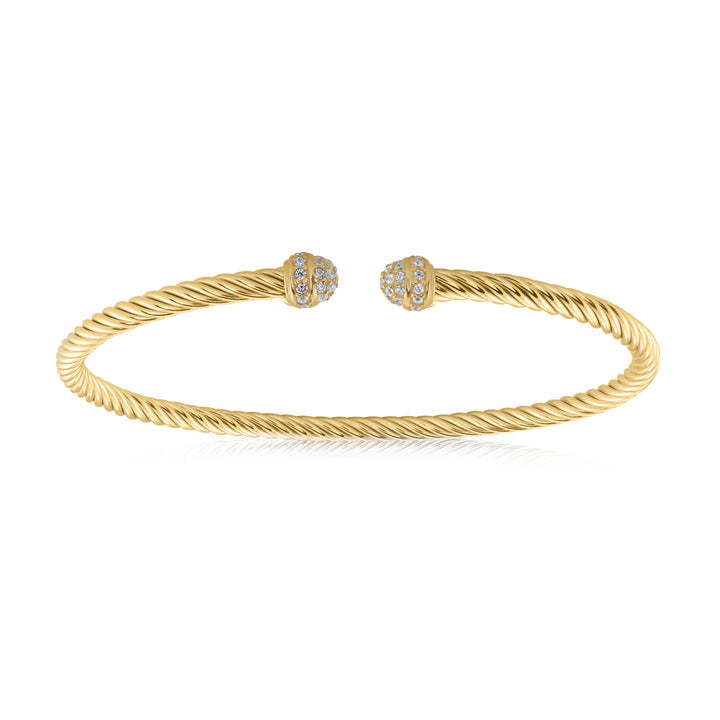 A gold cable-style cuff bracelet with two dome-shaped end caps paved with small clear stones, shown on a clean white background.
