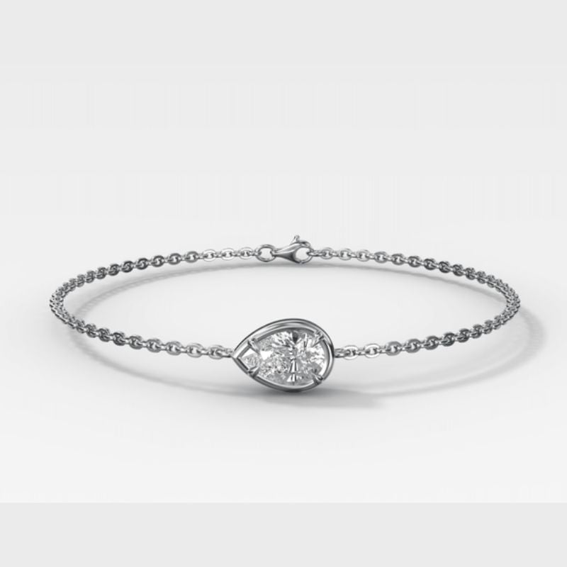 A silver chain bracelet featuring a teardrop-shaped clear gemstone in a polished bezel setting, displayed on a clean light gray background.