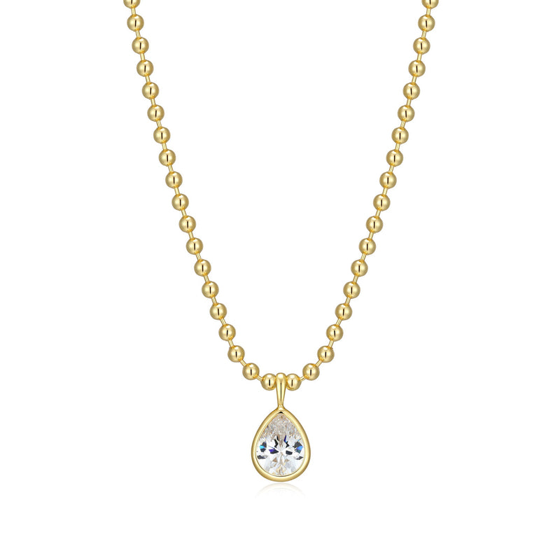 Gold bead ball necklace with a -pear cut bezel set Cubic Zirconia pendant on a white background 