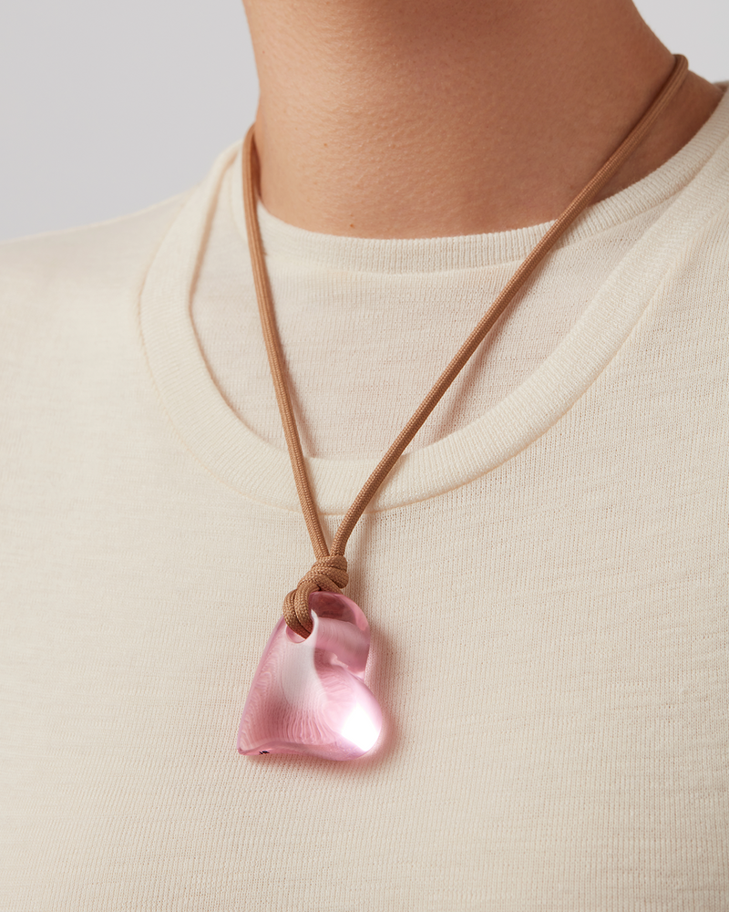 Model wearing pink recycled glass pendent on a sand string cord  by jenny Bird.