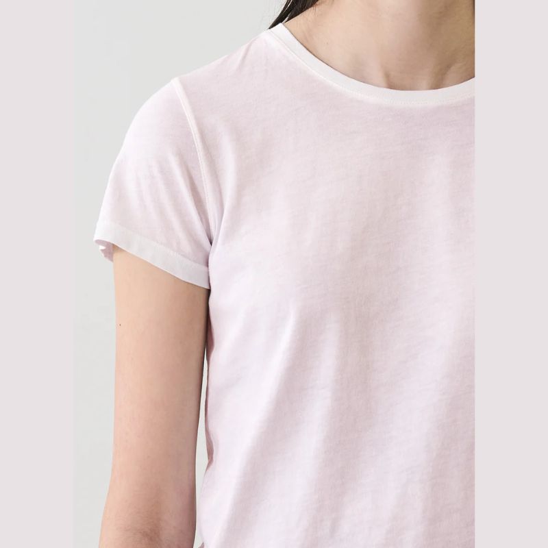 Person wearing a light pink  crewneck t-shirt against a plain background