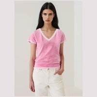 Woman wearing a pink t-shirt v- neck  with white trim on a plain background