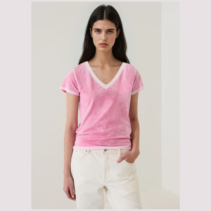 Woman wearing a pink t-shirt v- neck  with white trim on a plain background