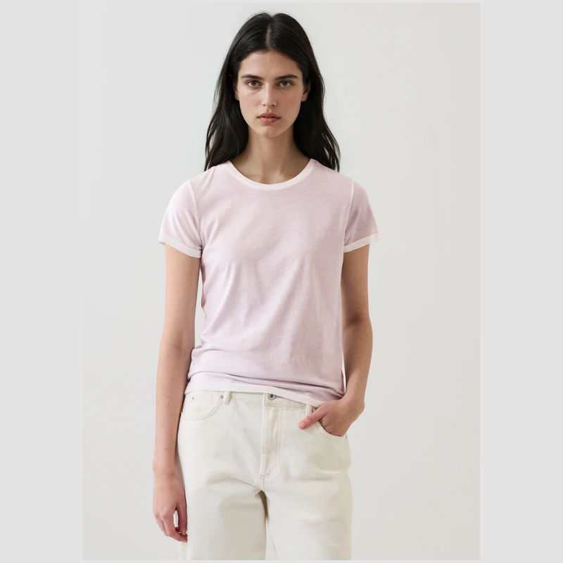 Woman wearing a light pink t-shirt and white pants on a plain background
