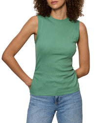 Woman wearing a green sleeveless top and blue jeans on a white background