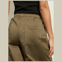 Person wearing olive green pants with a neutral background- Highlighting front 2 slant pockets 