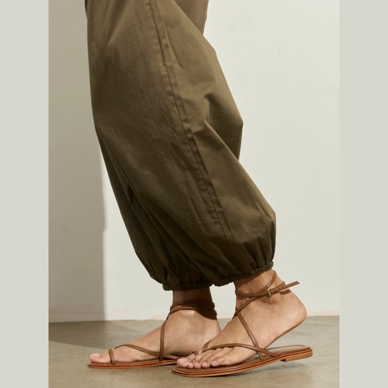 Person wearing brown sandals and Kalamata olive green relaxed fit pull on  pants on a neutral background