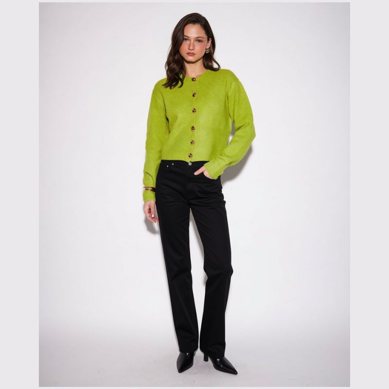 A woman modeling a lime green long-sleeve button-front cardigan with black pants and black pointed-toe heels, standing against a light gray studio background.