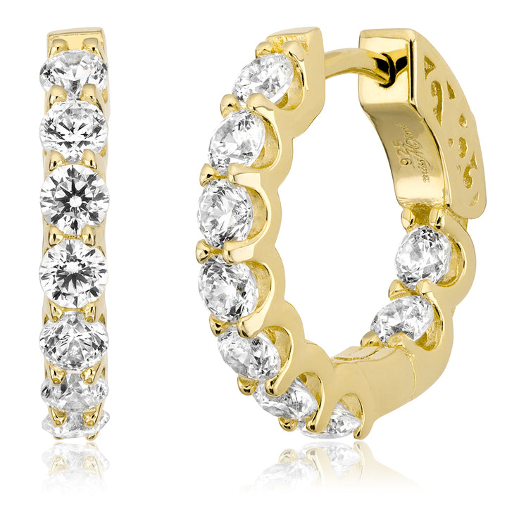 Gold huggie hoop earrings with a row of round clear gemstones, shown on a white background with one earring standing vertically and the other in profile.