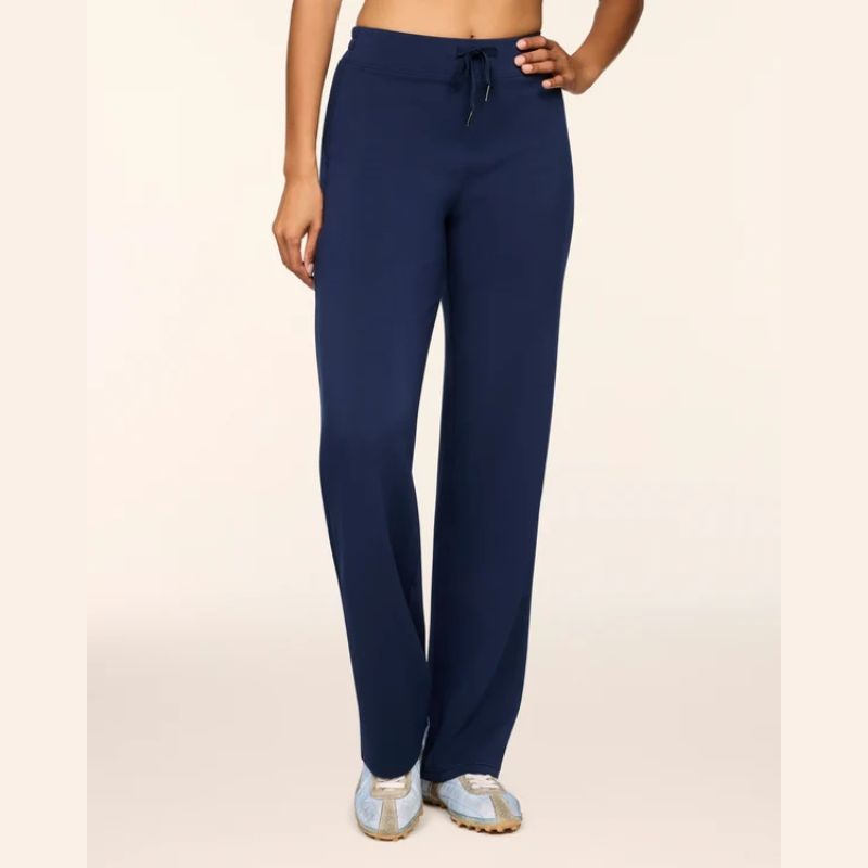 A model wearing navy blue drawstring sweatpants and light blue sneakers, shown from the waist down against a plain beige studio background.