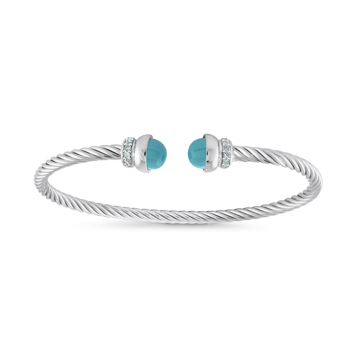 A silver cable-wrapped cuff bracelet with two round turquoise-blue cabochon stones, each accented with small clear stones, shown on a plain white background.
