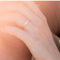 Close-up of a hand wearing a gold band ring with an inscription 