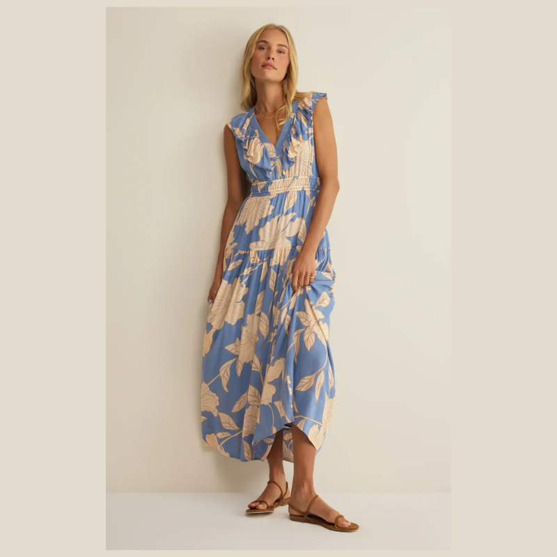 Woman wearing a blue and beige floral dress against a plain background. It has a  v- neckline, and an elastic waistband. 