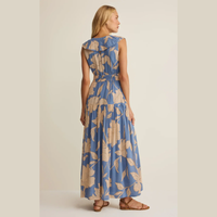 Back view of a Woman wearing a sleeveless blue and beige floral  maxi dress on a plain background