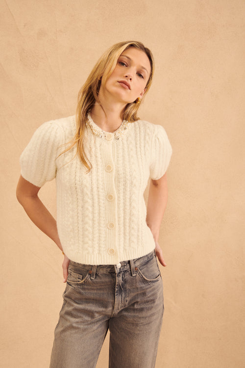 This elegant knit sweater has a pearl-encrusted collar, short sleeves, and front buttons. It's perfect for a special occasion or a night out.