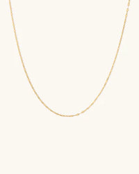 Gold chain necklace on a light beige background